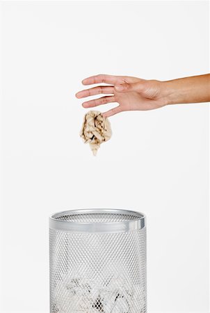 Close-up of a woman's hand throwing crumpled paper in a wastepaper basket Stock Photo - Premium Royalty-Free, Code: 625-01261211