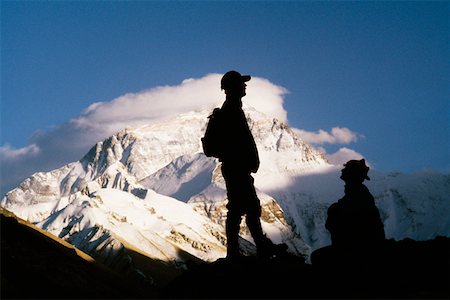 silhouette of man standing in a mountain top - Silhouette of two men on a mountain with snow covered mountains in the background, Mt Everest, Tibet, China Stock Photo - Premium Royalty-Free, Code: 625-01263928