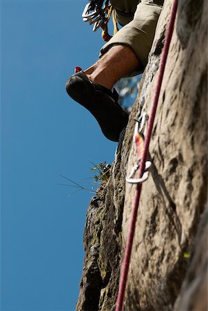 rock climbing closeup - Low angle view of a climbers' leg scaling a rock face Stock Photo - Premium Royalty-Free, Code: 625-01744228