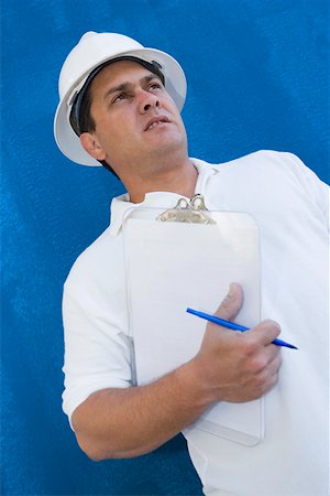 Low angle view of a male construction worker holding a clipboard and a pen Stock Photo - Premium Royalty-Free, Code: 625-01745833