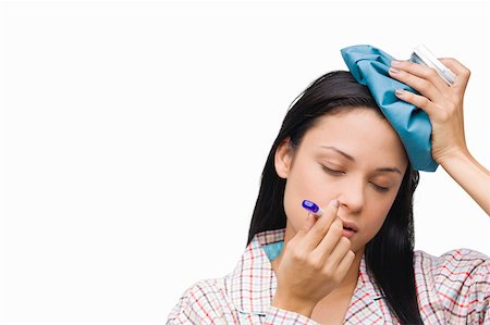 Close-up of a young woman measuring her temperature with a thermometer and holding an ice pack on her head Stock Photo - Premium Royalty-Free, Code: 625-01746336