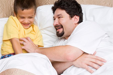 simsearch:625-00839074,k - Side profile of a mid adult man tickling his son on the bed Stock Photo - Premium Royalty-Free, Code: 625-01746422