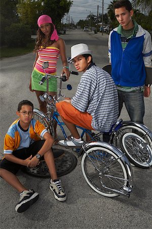 Portrait of a teenage boy on a low rider bicycle with his three friends beside him Stock Photo - Premium Royalty-Free, Code: 625-01746525