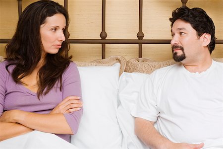 Close-up of a mid adult couple sitting on the bed and looking at each other Stock Photo - Premium Royalty-Free, Code: 625-01746899