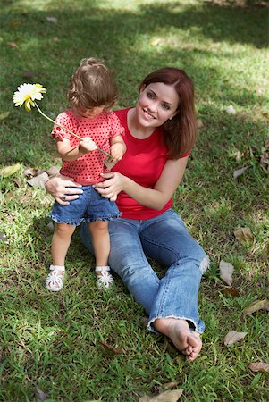 Young woman sitting on grass with her daughter and smiling Stock Photo - Premium Royalty-Free, Code: 625-01747056