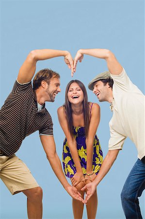 Mid adult man and a young man making a heart shape in front of a young woman Stock Photo - Premium Royalty-Free, Code: 625-01747133