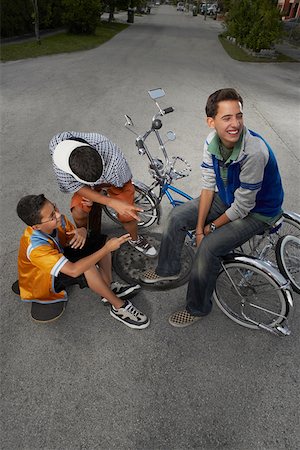 simsearch:625-01748893,k - High angle view of a teenage boy and a boy gesturing at their friend sitting on a low rider bicycle Stock Photo - Premium Royalty-Free, Code: 625-01747325