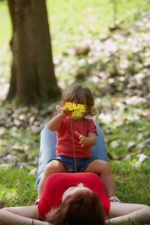 Young woman lying on grass with her daughter sitting on her stomach Stock Photo - Premium Royalty-Free, Code: 625-01747405