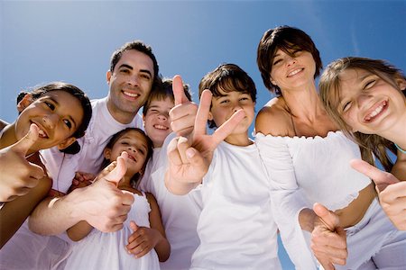 Portrait of a mid adult couple standing with five children making peace sign and thumbs up sign Stock Photo - Premium Royalty-Free, Code: 625-01748926