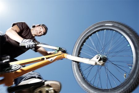 Low angle view of a young man performing a stunt on a bicycle Stock Photo - Premium Royalty-Free, Code: 625-02266411