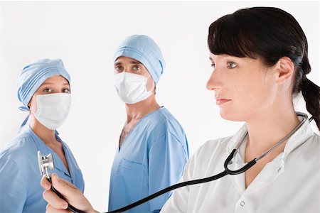 simsearch:625-02929180,k - Female doctor with two surgeons in the background Stock Photo - Premium Royalty-Free, Code: 625-02266704