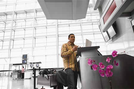 Faible angle vue d'un homme adult moyen à l'aide d'un ordinateur portable dans un aéroport Photographie de stock - Premium Libres de Droits, Code: 625-02266932