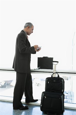 simsearch:625-02931717,k - Side profile of a businessman using a palmtop in the waiting room of an airport Stock Photo - Premium Royalty-Free, Code: 625-02267087