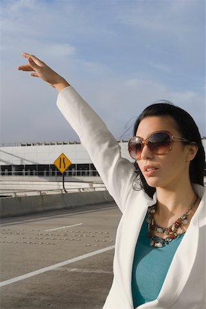 Close-up of a businesswoman hailing a taxi outside an airport Stock Photo - Premium Royalty-Free, Code: 625-02267091