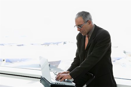 simsearch:625-02931717,k - Side profile of a businessman using a laptop in the waiting room of an airport Stock Photo - Premium Royalty-Free, Code: 625-02267111