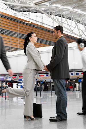 simsearch:625-02931998,k - Businessman and a businesswoman standing at an airport with holding each other's hands Stock Photo - Premium Royalty-Free, Code: 625-02267688