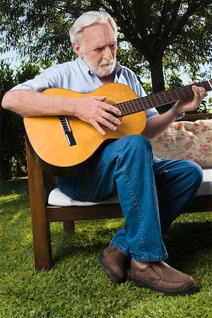 Senior man sitting on a couch and playing a guitar Stock Photo - Premium Royalty-Free, Code: 625-02267698