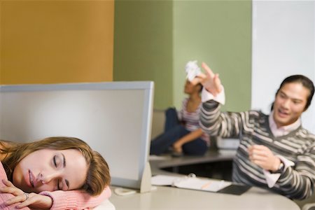 Close-up of a young woman napping and a young man throwing a crumpled paper on her Stock Photo - Premium Royalty-Free, Code: 625-02267781