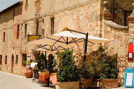 Potted plants and patio umbrellas in front of a building, Piazza Roma, Monteriggioni, Siena Province, Tuscany, Italy Stock Photo - Premium Royalty-Free, Code: 625-02928661