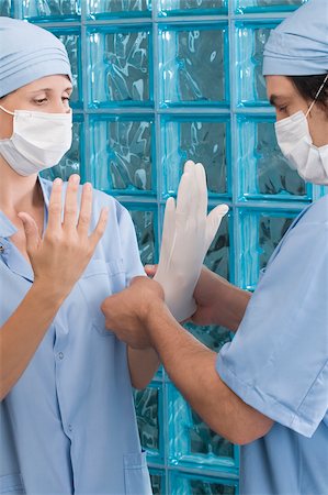 simsearch:625-02929180,k - Male surgeon adjusting a surgical glove of a female surgeon Stock Photo - Premium Royalty-Free, Code: 625-02929197