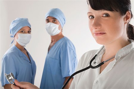 simsearch:625-02929180,k - Portrait of a female doctor with two surgeons in the background Stock Photo - Premium Royalty-Free, Code: 625-02929200
