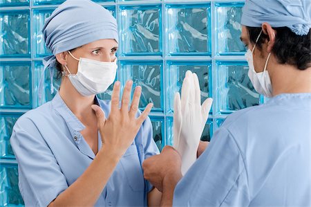 simsearch:625-02929180,k - Male surgeon adjusting a surgical glove of a female surgeon Stock Photo - Premium Royalty-Free, Code: 625-02929230