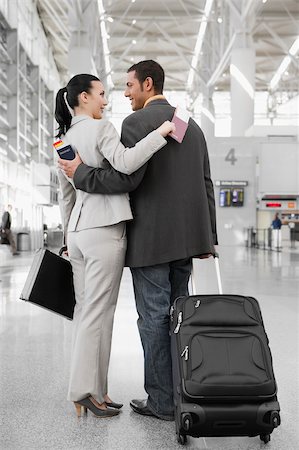 simsearch:625-02929600,k - Businessman and a businesswoman standing at an airport with their arms around each other Stock Photo - Premium Royalty-Free, Code: 625-02929598