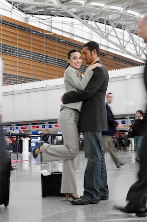 simsearch:625-02929600,k - Side profile of a businessman and a businesswoman hugging each other at an airport Stock Photo - Premium Royalty-Free, Code: 625-02929601