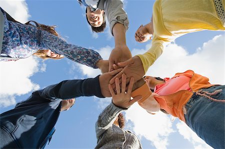 Low angle view of university students stacking their hands in a huddle Stock Photo - Premium Royalty-Free, Code: 625-02929675