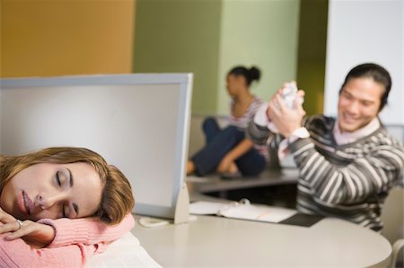 Young woman napping on a desk with a young man smiling in the background Foto de stock - Sin royalties Premium, Código: 625-02929712