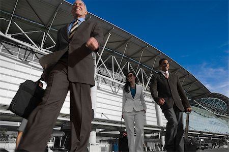 simsearch:625-02929600,k - Low angle view of two businessmen with a businesswoman walking outside an airport Stock Photo - Premium Royalty-Free, Code: 625-02929946