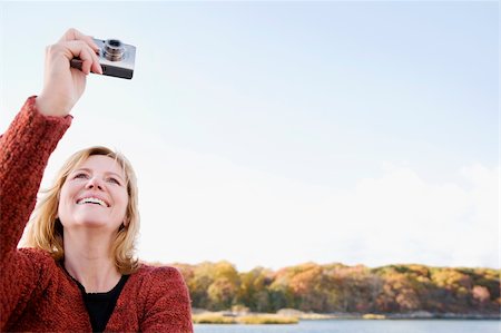 Mature woman photographing with a digital camera and smiling Stock Photo - Premium Royalty-Free, Code: 625-02930251