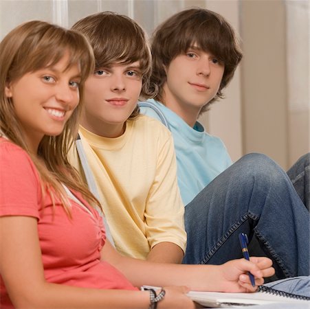 Portrait of a teenage girl smiling with her friends sitting beside her Stock Photo - Premium Royalty-Free, Code: 625-02930315