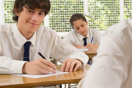 Portrait of a young man writing on paper sheet and smiling with a teenage girl behind him Stock Photo - Premium Royalty-Free, Code: 625-02930311