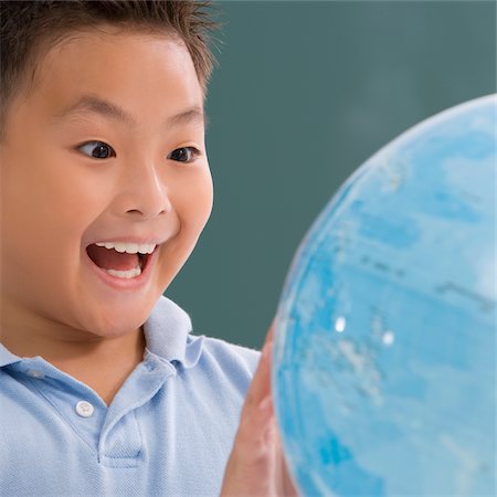 Close-up of a schoolboy looking at a globe and laughing Stock Photo - Premium Royalty-Free, Code: 625-02930427