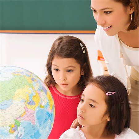 Two schoolgirls with a female teacher looking at a globe Foto de stock - Sin royalties Premium, Código: 625-02930436