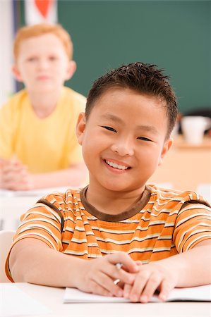 Portrait of a schoolboy smiling in a classroom Stock Photo - Premium Royalty-Free, Code: 625-02930455