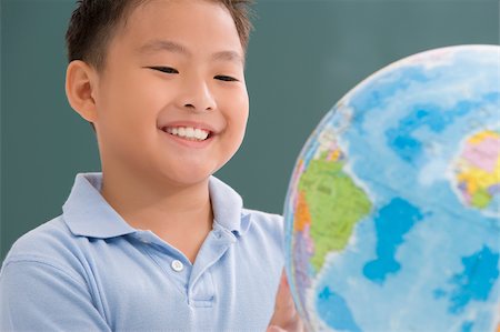 Close-up of a schoolboy looking at a globe in a classroom Stock Photo - Premium Royalty-Free, Code: 625-02930479