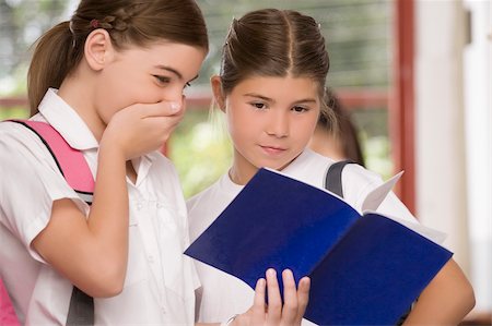 Close-up of a schoolgirl showing her textbook to another schoolgirl Stock Photo - Premium Royalty-Free, Code: 625-02930927