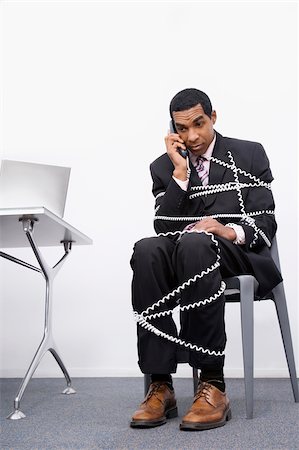 Businessman trapped in a wire of a telephone Stock Photo - Premium Royalty-Free, Code: 625-02931407