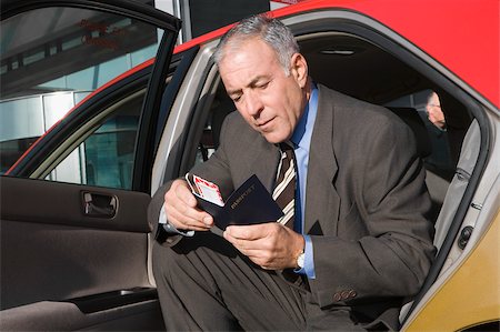 simsearch:625-02931717,k - Businessman sitting in a taxi and checking his passport Stock Photo - Premium Royalty-Free, Code: 625-02931784