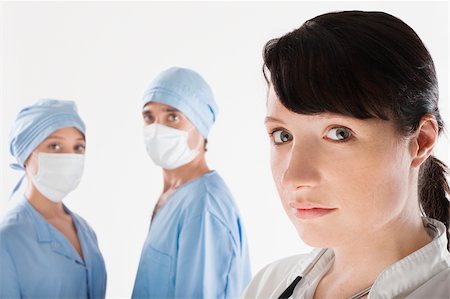 simsearch:625-02929180,k - Female doctor with two surgeons in the background Stock Photo - Premium Royalty-Free, Code: 625-02931830