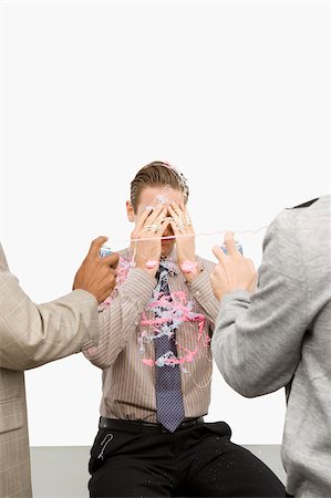 Rear view of two businessmen spraying a businessman with silly string Stock Photo - Premium Royalty-Free, Code: 625-02932664