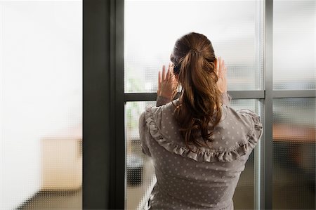 Rear view of a businesswoman looking through a window Stock Photo - Premium Royalty-Free, Code: 625-02933008