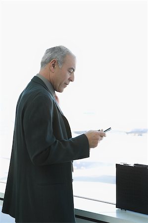 simsearch:625-02931717,k - Side profile of a businessman operating a personal data assistant at an airport Stock Photo - Premium Royalty-Free, Code: 625-02933170