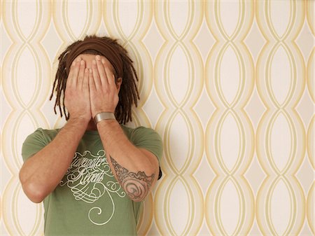 Man with dreadlocks in front of old-fashioned wallpaper Stock Photo - Premium Royalty-Free, Code: 628-05817800