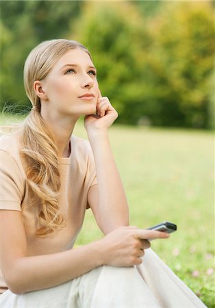 Young blond woman sitting outdoors with cell phone Stock Photo - Premium Royalty-Free, Code: 628-05817819