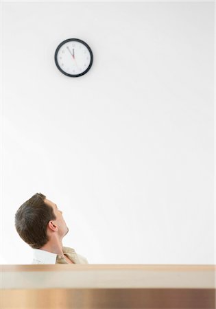 Man looking back on a wall clock Stock Photo - Premium Royalty-Free, Code: 628-05817881