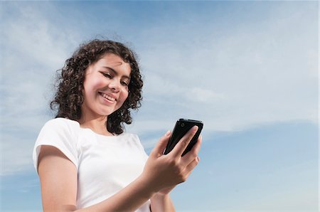 simsearch:628-07072097,k - Smiling girl outdoors looking on cell phone Stock Photo - Premium Royalty-Free, Code: 628-07072105
