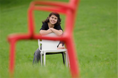 simsearch:628-07072097,k - Smiling girl with plastic chair sitting in meadow Stock Photo - Premium Royalty-Free, Code: 628-07072122
